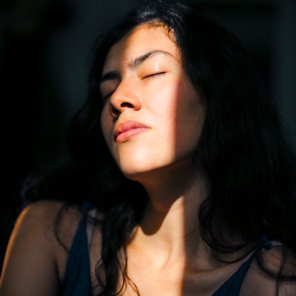 Woman meditating peacefully with a calm expression on her face.